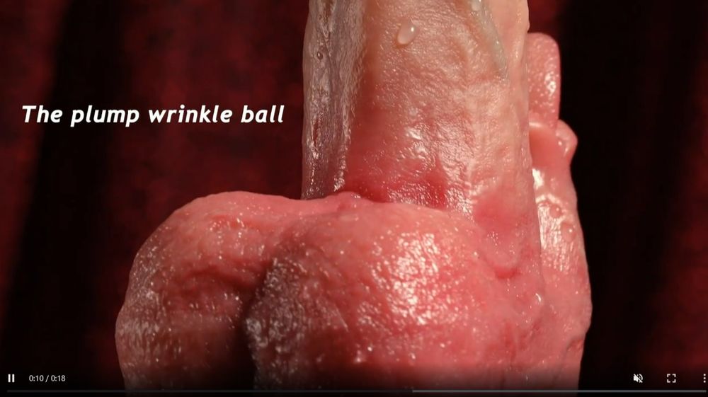 An ad with a close up on the scrotum of a weird, hyper realistic dildo that consists of a cock and balls with an attached miniature set of lips and tongue for clit stimulation. Text proclaims "the plump wrinkle ball"