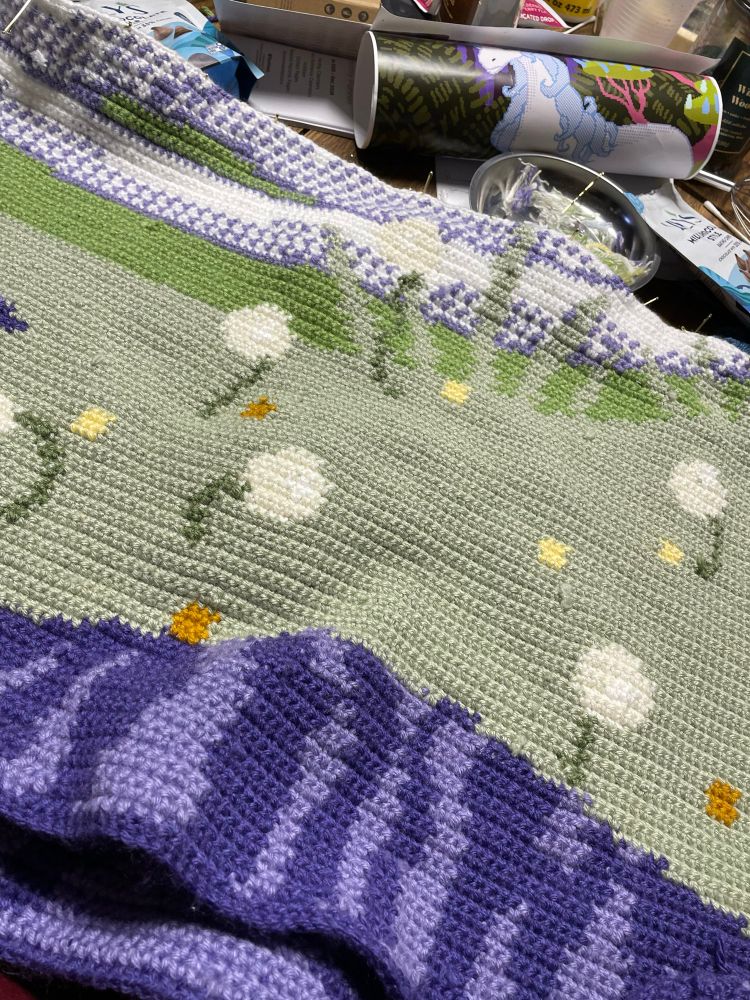 Close up pic of a crochet WIP featuring what will eventually be the back part of the unicorn with a lot more dandelions than the first image 