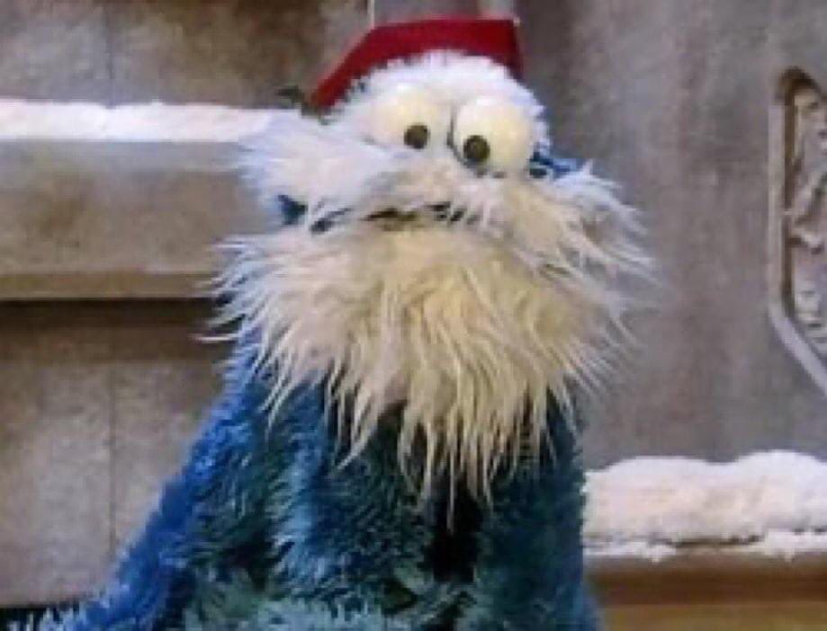 Cookie Monster as Santa Claus with crossed eyes the scraggliest beard possible for a muppet