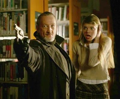 Robert Englund is dressed in a big coat, he's holding a revolver, the girl he's protecting is covering her ears 