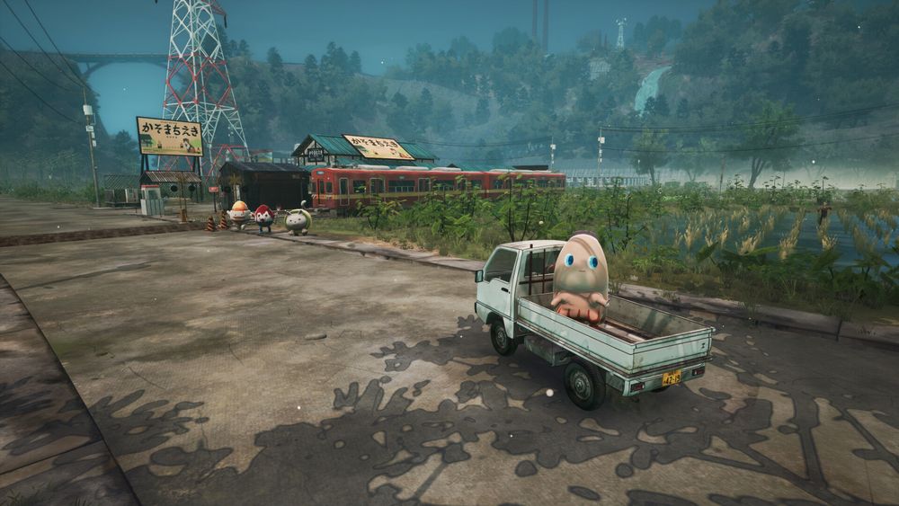 Screenshot from Promise Mascot Agency, showing the little white kei truck with Pinky (a severed pinky finger mascot) in the back, there's a train station in the backgrounds along with rice fields. It's very pleasant. 