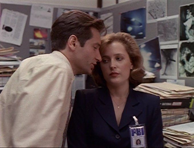 Murder leaning in real close to Scully, her expression is "sick of his shit"