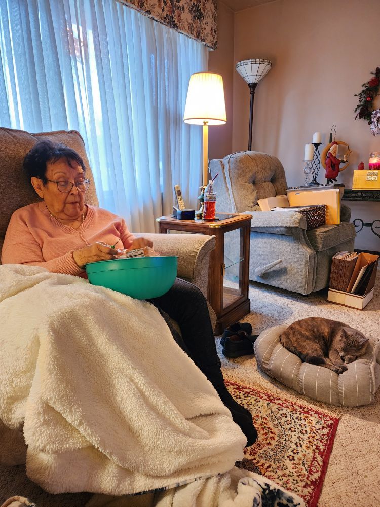 Grandmother sitting in a reclining chair with a cat sleeping near her feet