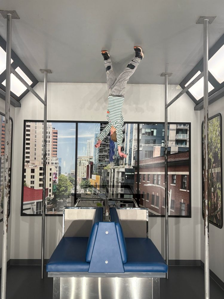 Image in which it appears that a child in a striped shirt is suspended upside down from the ceiling of the Seattle monorail 