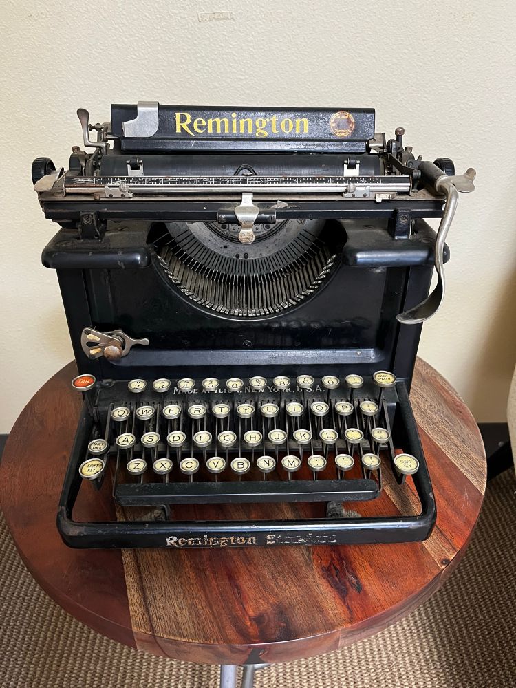 A black standard typewriter. It looks like it weighs a ton (it does). A gold Remington decal adorns the paper tray. Interestingly, it has the return lever on the right side, not the more common left. 