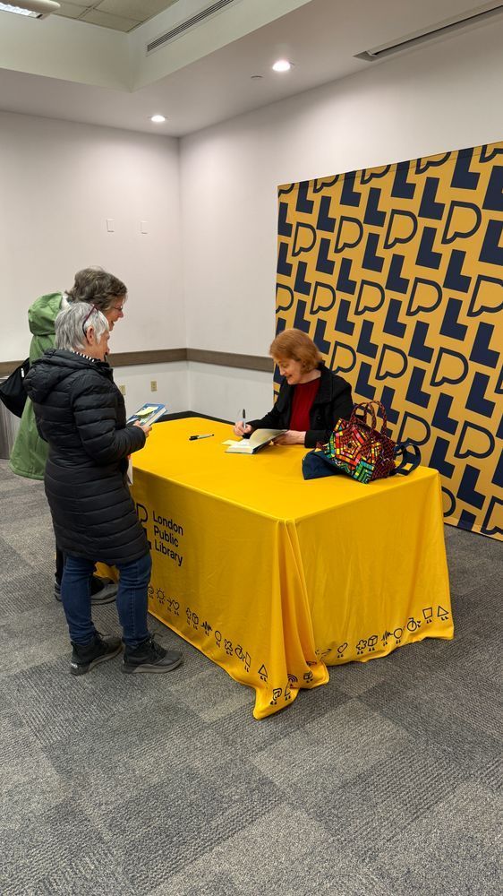 Author Emma Donoghue signing a copy of her book for two women. 