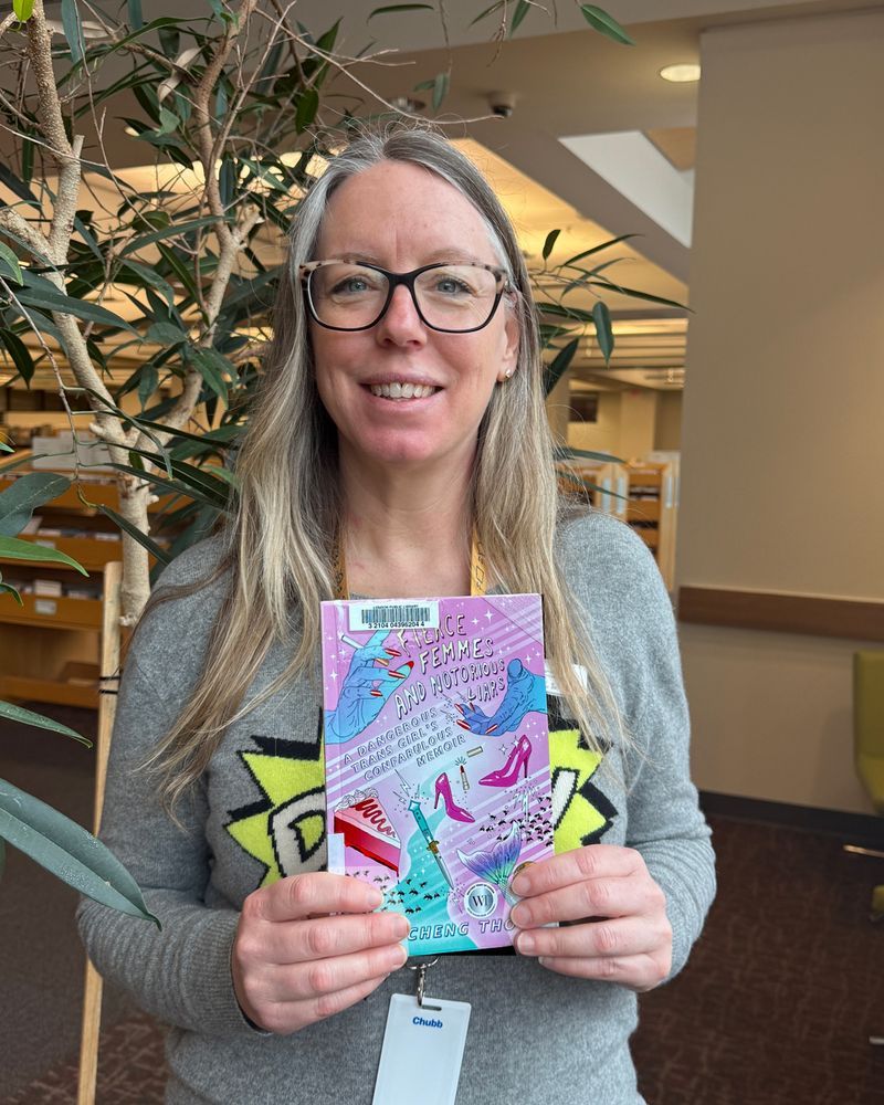 A Library staff person holding the book 
Fierce femmes and notorious liars: A Dangerous Trans Girl's Confabulous Memoir by Kai Cheng Thom.