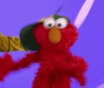 elmo from sesame street is wearing a green hat and holding something .