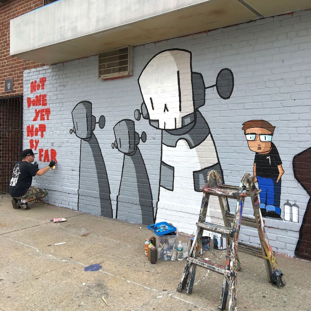 Artist ChrisRWK paints a mural for Welling Court Mural Project in Astoria in Queens, New York.