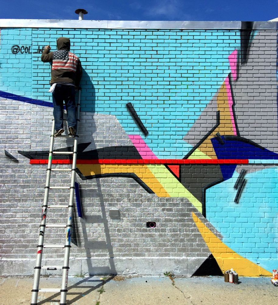Col Wallnuts paints a mural for Welling Court Mural Project in Queens, New York. 