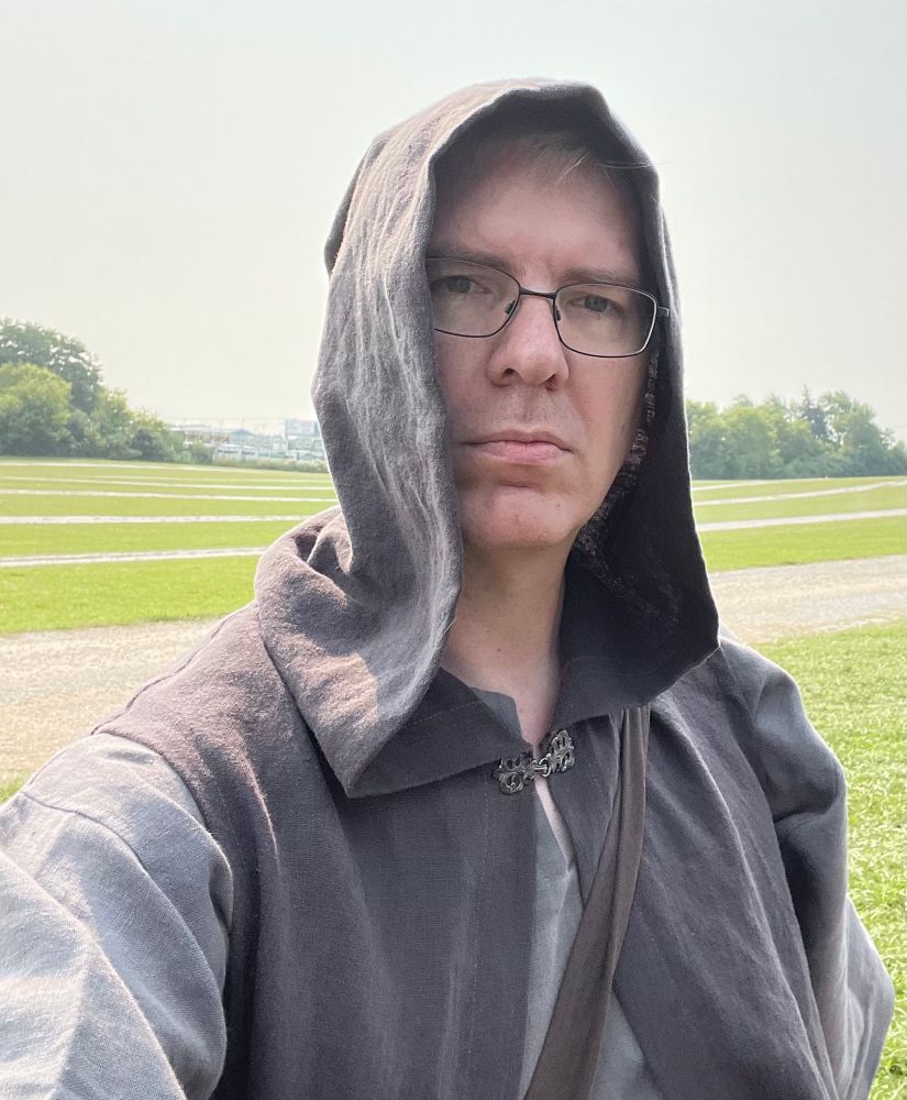 Selfie. Light gray shirt with dark gray tunic and hood over. 