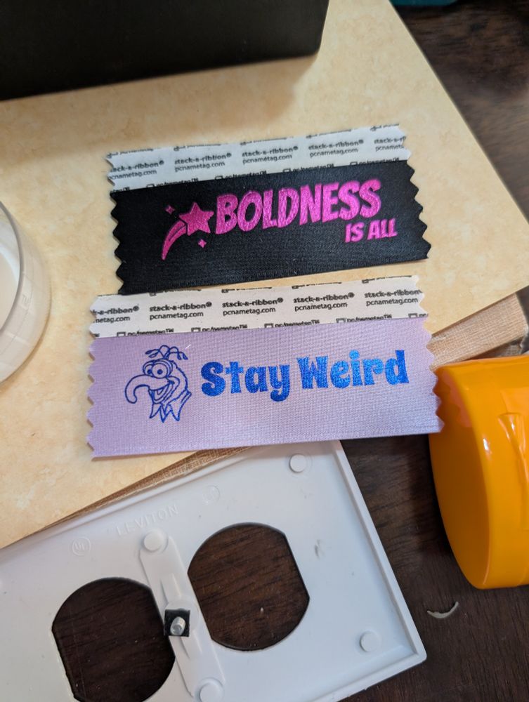 two badge ribbons, one reading "boldness is all" the other "stay weird" with a picture of gonzo