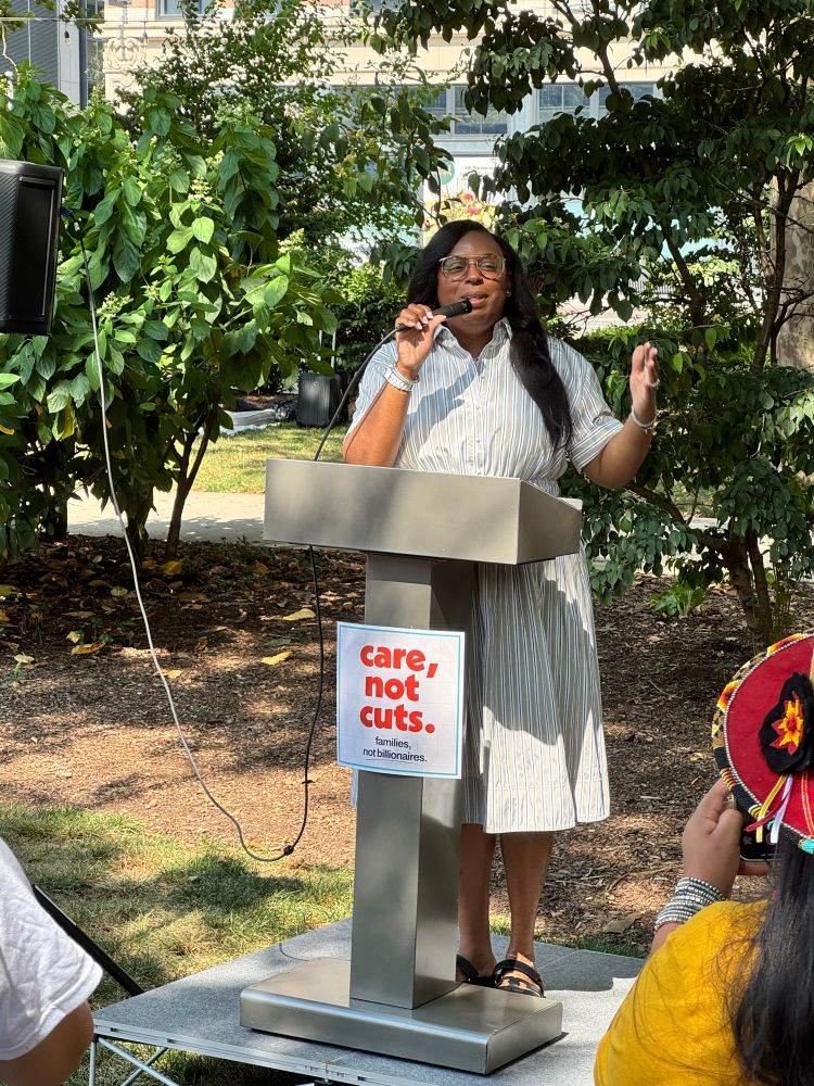A woman in a dress speaking at a podium.