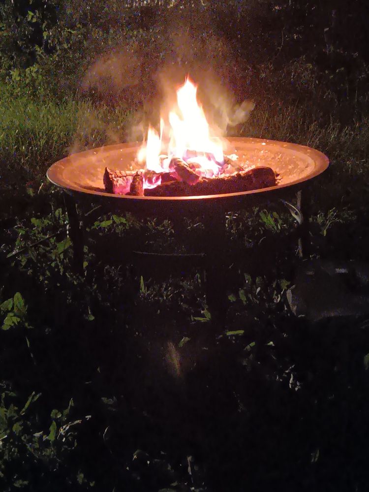 Fire in an elevated basin with green grass all around.