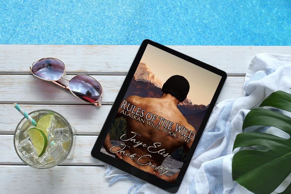 Poolside scene with a copy of Rules of the Wild by Jaye Elise and Jack Crosby displayed on an iPad.