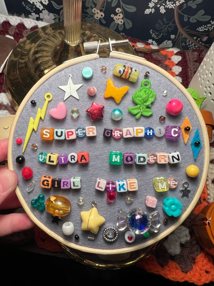 chaotic charm embroidery hoop with lyrics from chappell roan’s song “super graphic ultra modern girl like me” 
