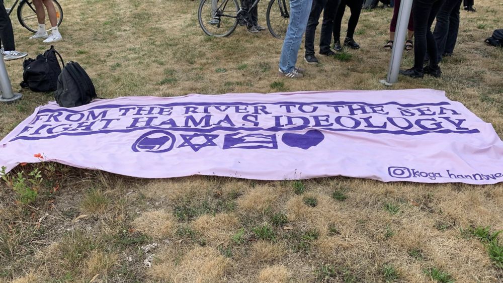 ein Transparent auf dem Rasen
Text: "From the river to the sea
Fight Hamas Ideology!"
Darunter
Antifa Flagge, Magen David, Palästina Flagge und ein Herz