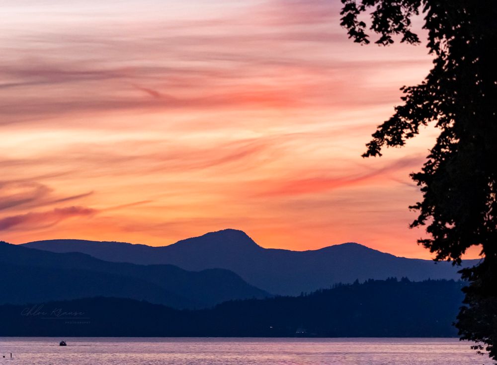 Orangey sunset over mountains and the ocean. 