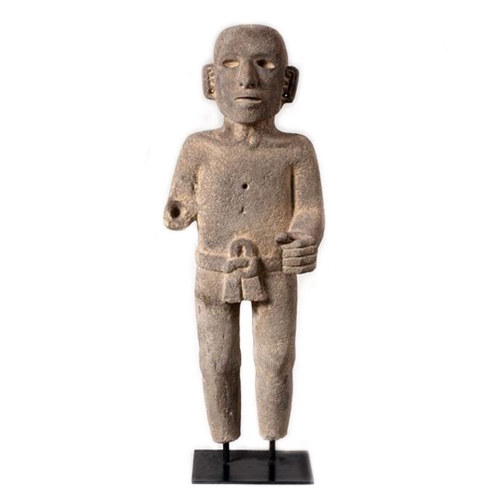 Carved between 1200 and 1500
AD, this rare 29-inch Aztec standing figure was once a standard bearer. He wears a loincloth with a large knot at the front, and his left hand is clenched, ready to hold a ceremonial pole. His chest still bears two shallow holes... evidence of inlays now lost to time.
Made of gray basalt with striking facial features and a simplified form, this sculpture speaks of ritual, strength, and sacred duty.
