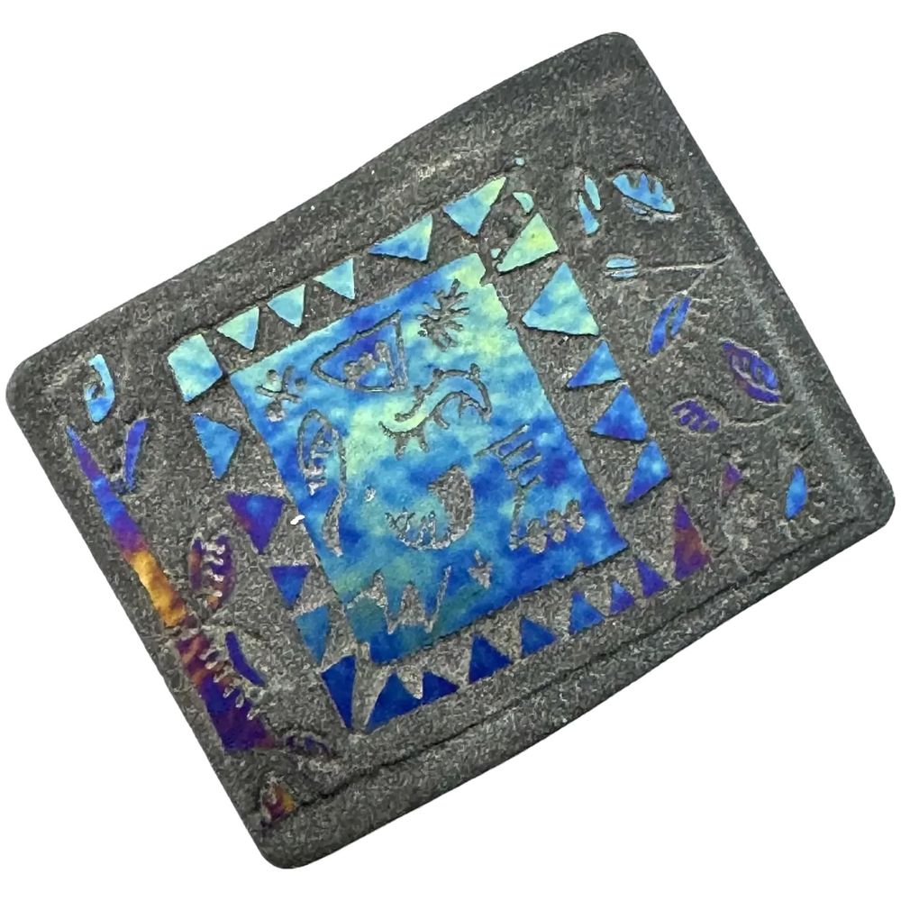 A unique vintage 1970s one of a kind handmade titanium on pottery Tribal modernist figures design brooch. The image at front is revealed when the angle of the light reaches a certain angle, and the figures look like ancient pictographs perhaps inspired by the famous Lascaux cave drawings. Looks like the titanium coating was cut-thru at front to reveal the black pottery base. Very unusual, never seen another! Measures 2" wide by 1-5/8" tall at front. Unmarked, and I'm guessing was originally sold through an art gallery or fair with accompanying paperwork or labeling that has been lost over the years. No doubt a one of a kind piece of wearable art! Excellent vintage condition.