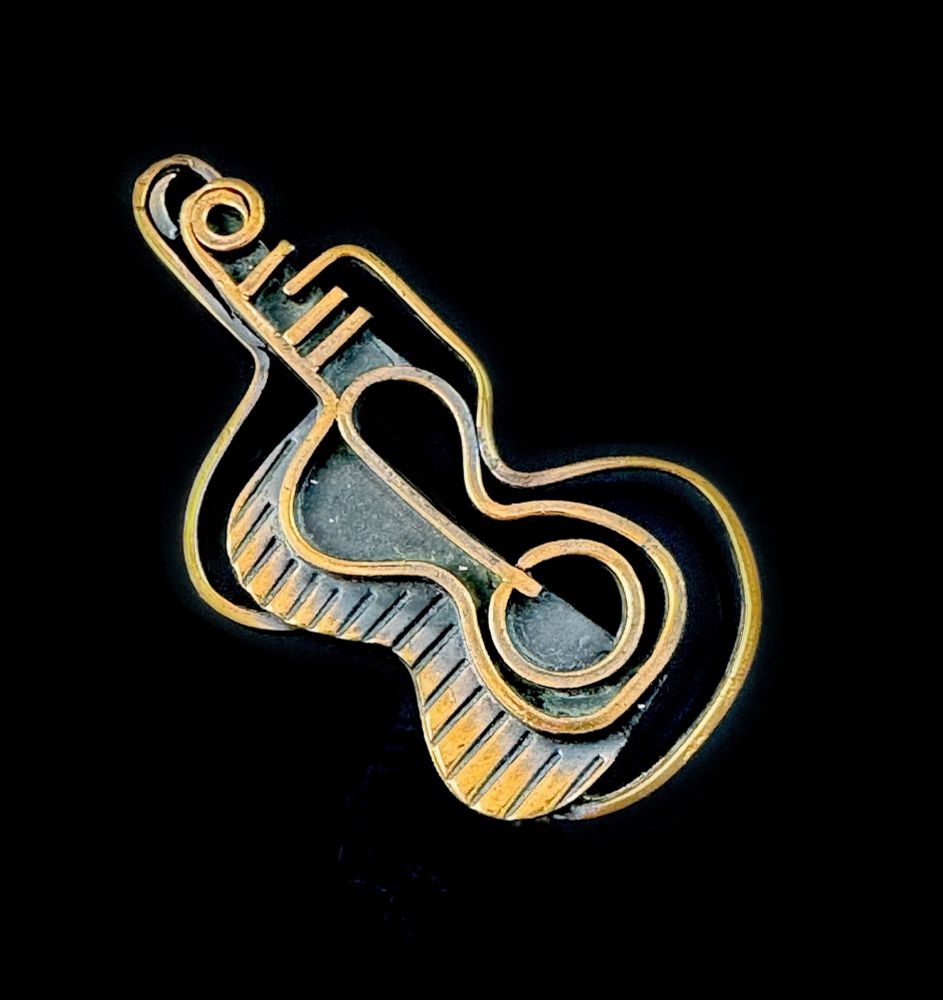 A very large and rare vintage 1950s handmade copper modernist Guitar design brooch pin by Francisco Rebajes of NYC. One of the rarer and more sought-after designs by Rebajes from the period! Constructed of solid copper that has been oxidized (black) in the recesses, and then given a clear coating to prevent tarnishing. 'Frank' Rebajes was one of the earliest self-trained studio metalsmiths in the US, starting back in the early 1930s. He quickly went from selling his idiosyncratic jewelry creations on the street to a posh and stylish showroom on 5th Avenue in the 1940s! He sold his business in 1958, and moved to Torremolinos Spain where he worked on his famous Ovulos sculptures and one of a kind pieces of jewelry and decorative art. 
This brooch measures 3" long by 1-1/2" wide. Could also be worn as a pendant with the addition of a bail-ring at top. Marked at back, "Rebajes" with his unique stylized mark. Excellent vintage condition.
