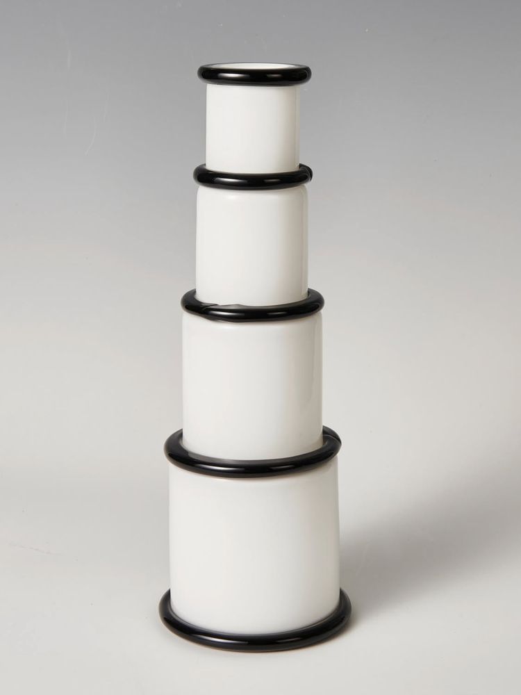 VASE, model 'Morosina', designed 1974 for Vistosi, limited edition of 250.

Ettore Sottsass, 'Morosina' vase, 1974, 
Made by Vetreria Vistosi, Murano. 
Overlaid glass, colorless and white, attached ribbons made of black glass. 
Marked: E. SOTTSASS 202/250 Vistosi 
Barovier / Bischofberger / Carboni, Sottsass Glass works, Stuttgart 1998, p. 16.
Number 202 from a limited edition of 250
White and black glass. 
Signed, inscribed and numbered below: E. SOTTSASS 201/250 VISTOSI.Ø 14 cm; H 39 cm. 