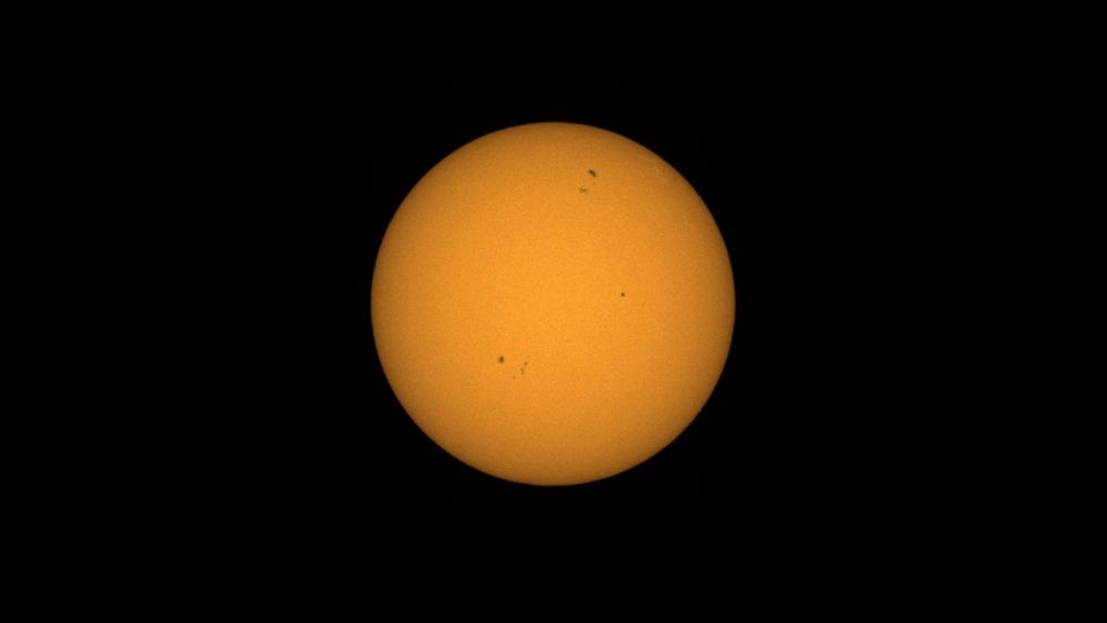 A perfectly spherical yellow globe on a black background. It looks like a hard boiled egg yolk but is in fact, the sun