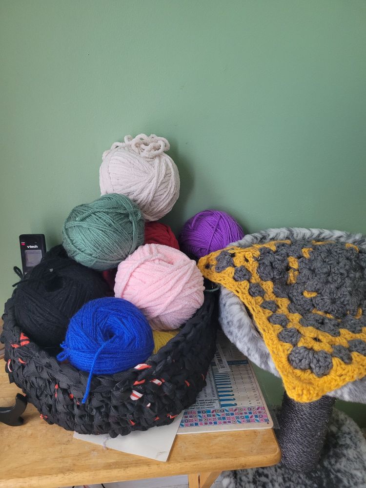 This is the table that has a basket made of plarn holding many different balls of yarn. 