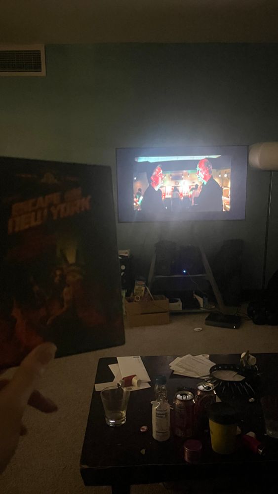 A tv in which escape from New York is playing while I hold up the cover of the dvd box. Escape from New York 