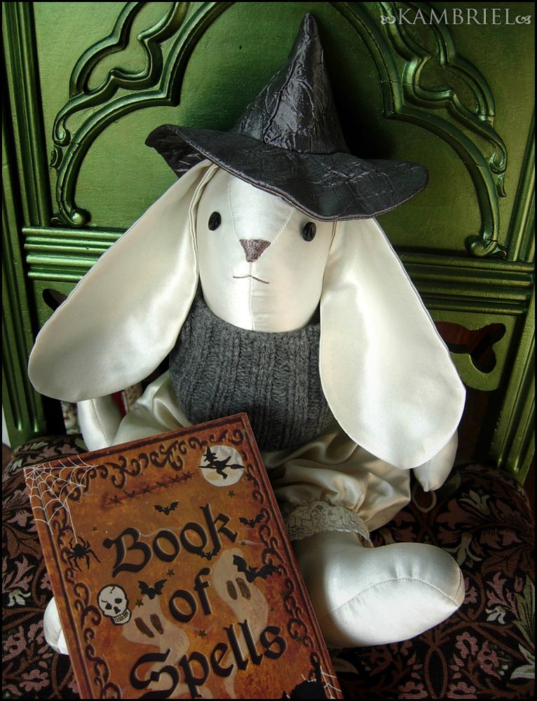 Adorable handmade bunny made from vintage ivory sateen & wearing a silver witch hat and handknit grey sweater while perched atop a gothic green chair with a luminous gleam. (bun & photo by: Kambriel)