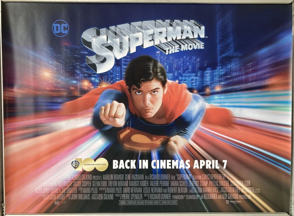 vibrant, digitally-rendered movie poster for 1978's "Superman: The Movie" directed by Richard Lester. It features a determined Superman, with his iconic red and blue suit, flying through a blurred cityscape at night. The background showcases streaks of light, giving a sense of speed. The title "SUPERMAN THE MOVIE" is prominently displayed in bold, metallic letters at the top, with the DC logo on the left. The release date "BACK IN CINEMAS APRIL 7" is written in white text at the bottom. The overall style is dynamic and action-packed.