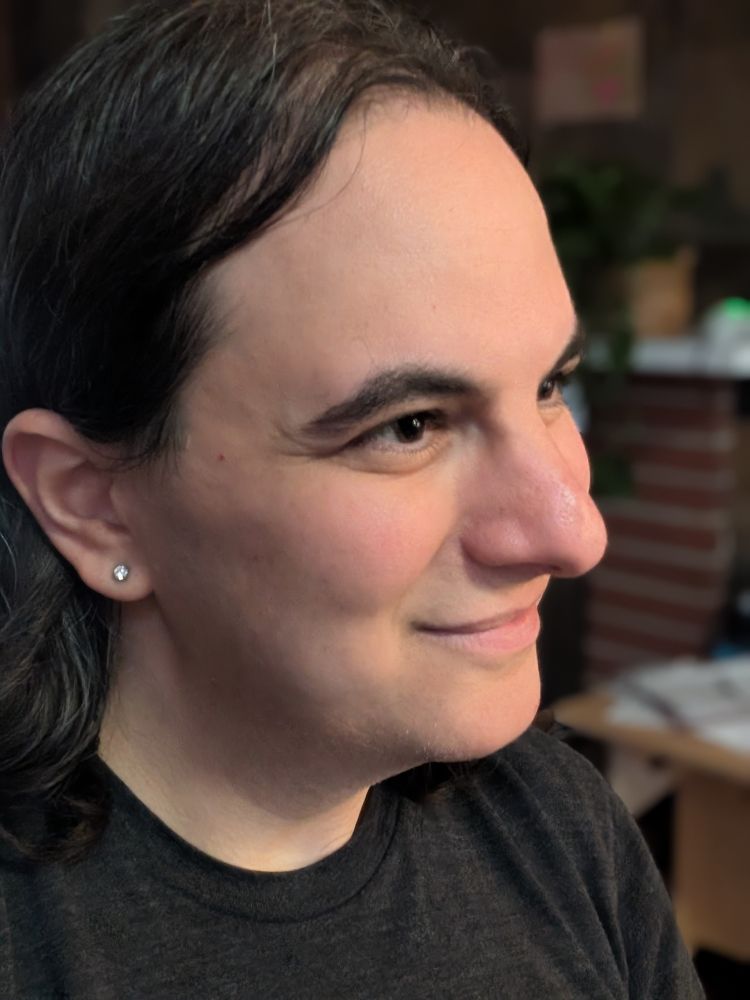 The author in a selfie portrait, wearing a black shirt and with her earrings glinting.