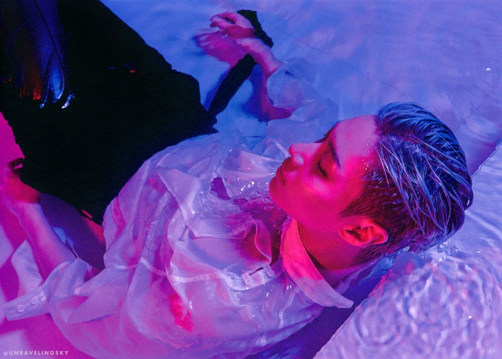 Move era, he has an undercut and silver hair, he is laying in like a bath tube or pool with black trousers and a white button down shirt, and is seen from the back/side