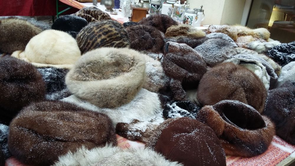 a heap of snowdusted fur hats, on a makeshift table, glimpses of a foreign century