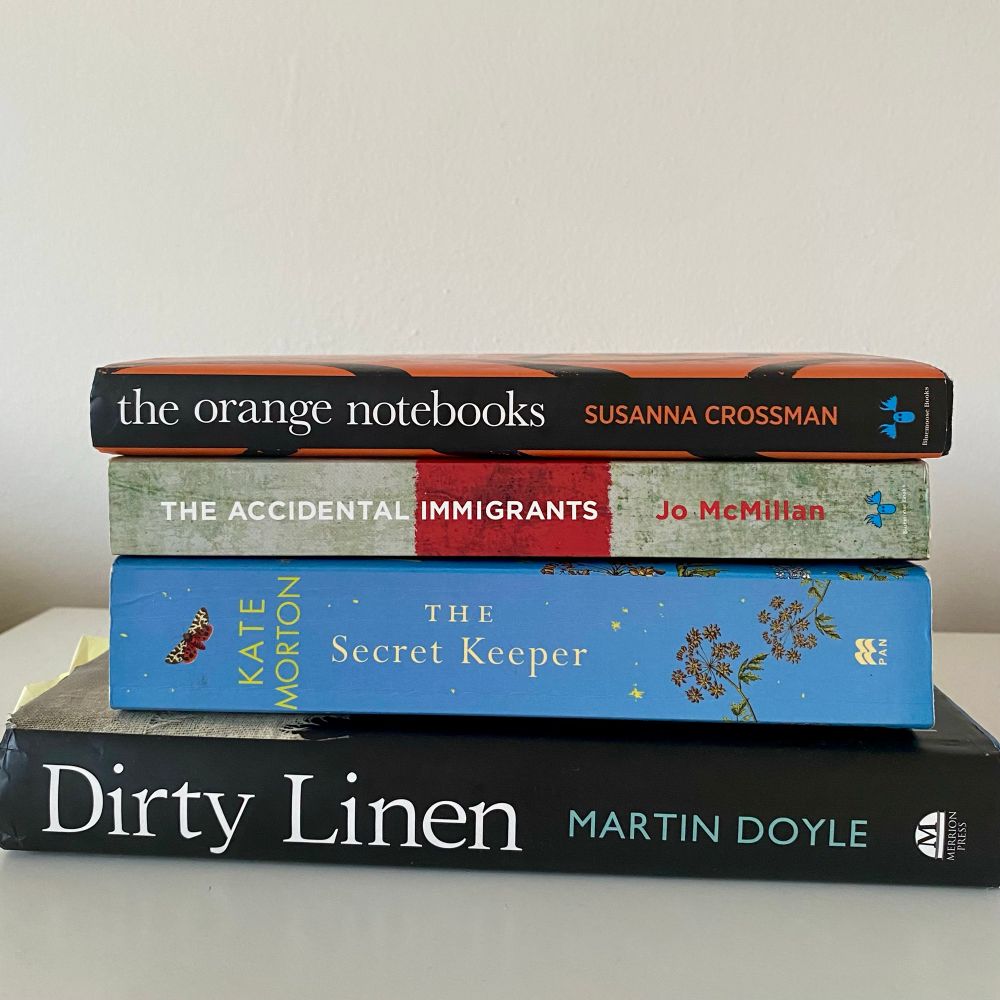 Four books sitting in a white table.