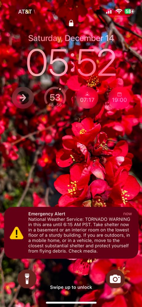 iPhone Lock Screen with a notification that reads:
Emergency Alert
now
National Weather Service: TORNADO WARNING in this area until 6:15 AM PST. Take shelter now in a basement or an interior room on the lowest floor of a sturdy building. If you are outdoors, in a mobile home, or in a vehicle, move to the closest substantial shelter and protect yourself from flying debris. Check media.
