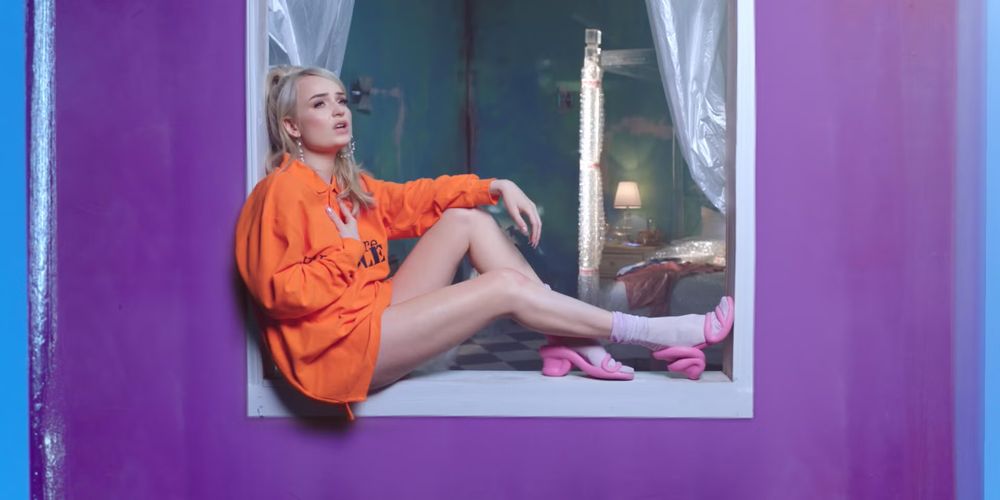Kim Petras in the Heart To Break video looking plaintive and sitting on a window sill 