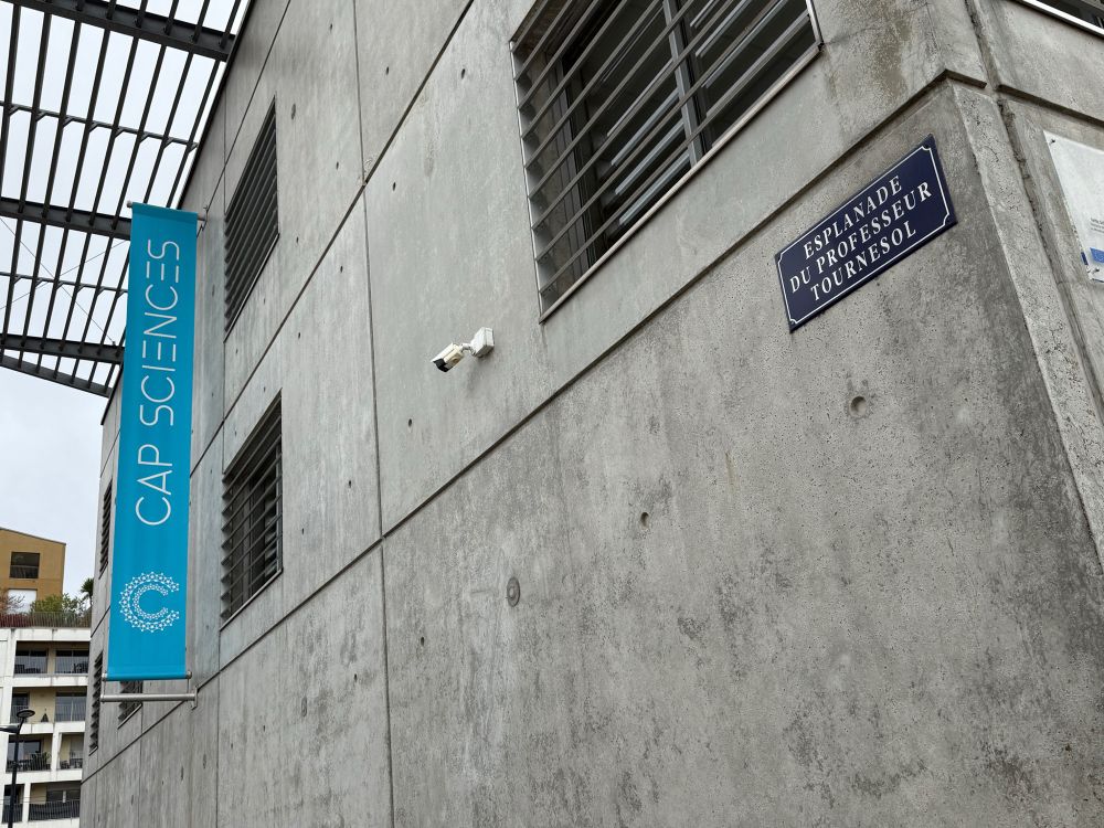 Foto van Cap Sciences in Bordeaux met een straatnaambordje van de Esplanade de Professeur Tournesol. 