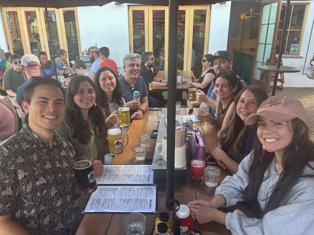 A group of three men and five women sitting at a picnic table outside a restaurant in Leavenworth, Washington enjoying a drink on a lovely summer evening.