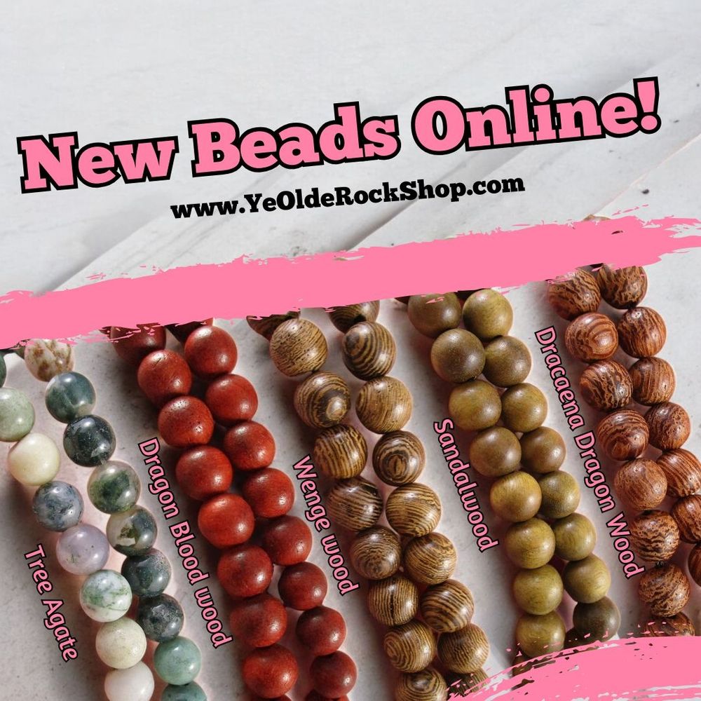 4 strands of wood beads (one red, three brown) and one strand of tree agate beads (white and green) spread on a counter. 
