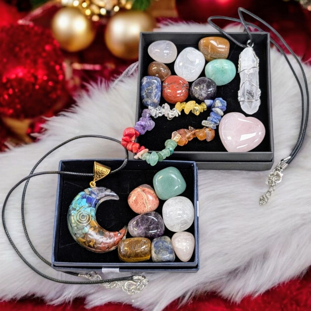 A Christmas scene with fuzzy white and red blankets. On the blankets are 2 boxes full of crystals and jewelry.