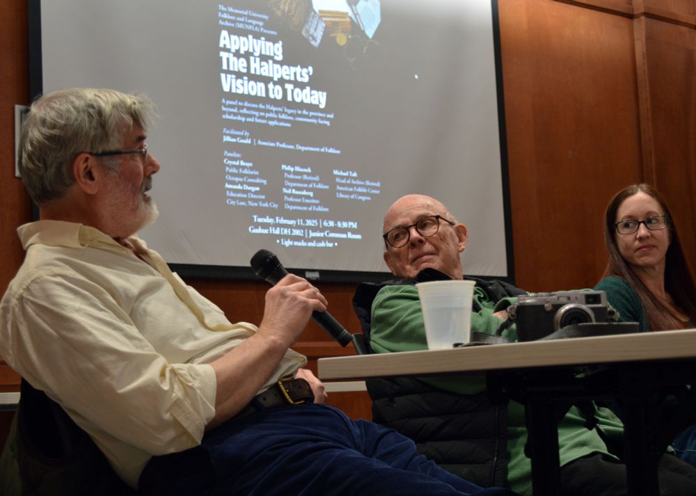 Panelists (L-R) Philip Hiscock, Neil Rosenberg, and Crystal Braye. Braye and Rosenberg look on as Hiscock speaks into a microphone. 