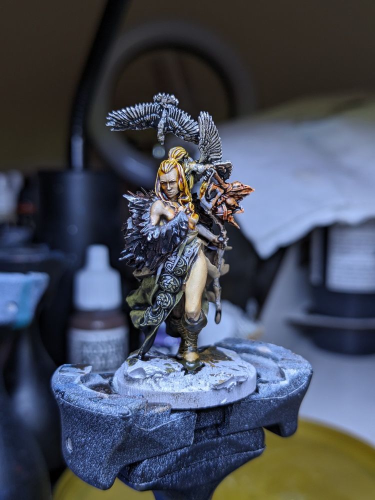 A half painted model of a barbarian type priestess surrounded by crows.