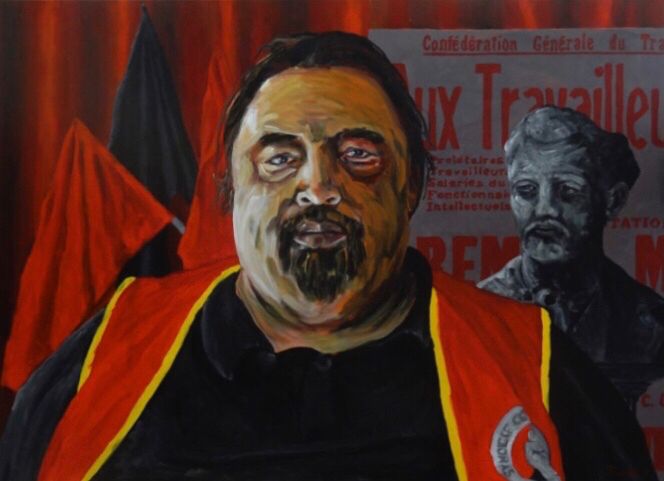 Portrait de Bruno F, en buste, posant devant une vieille affiche de la Cégète et un buste de Jules Durand, militant mort en 1926 au CH du Rouvray.