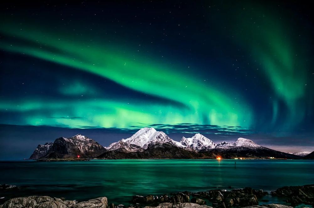 A lake and mountain under northern lights in the sky.