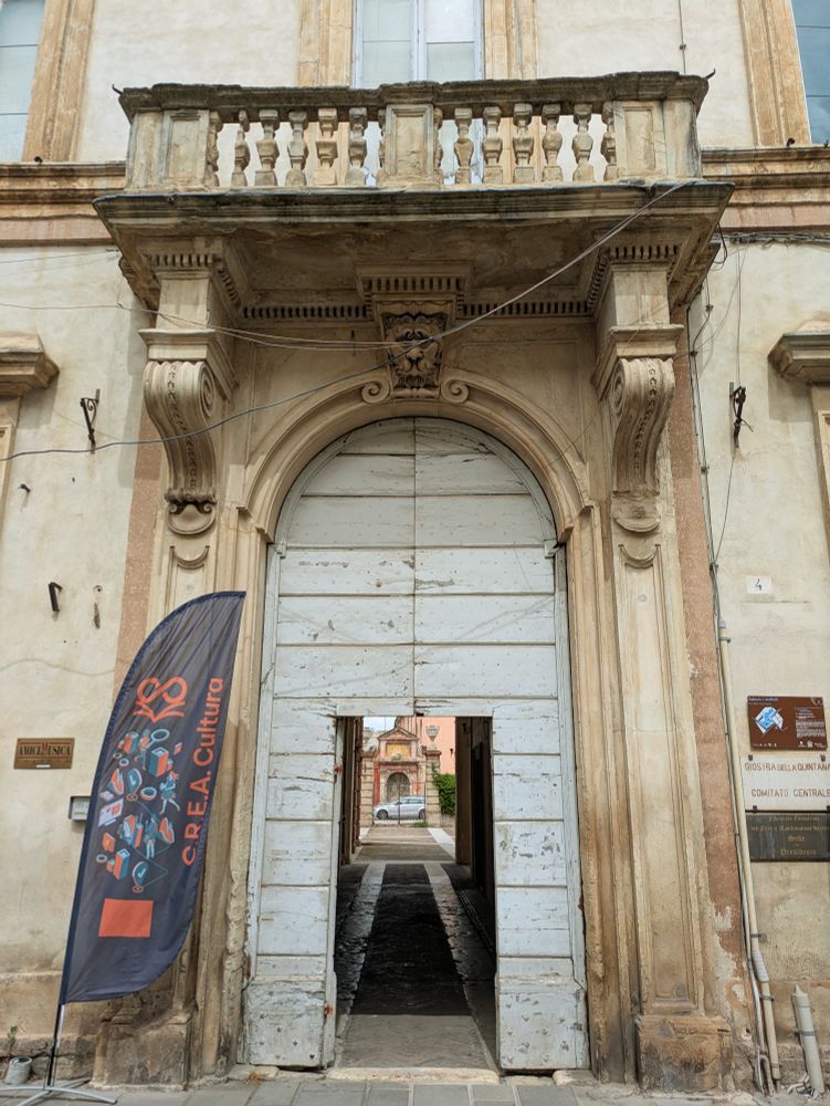 The entrance to the CREA Cultura festival, which is a large wooden door under a stone balcony; a CREA Cultura flag sits next to the door.