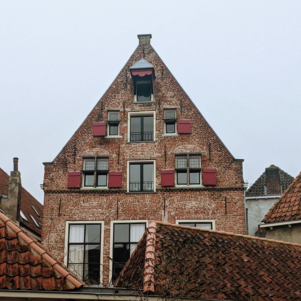 Photo depicting an A-frame red brick house with red shutters in Deventer, Netherlands.