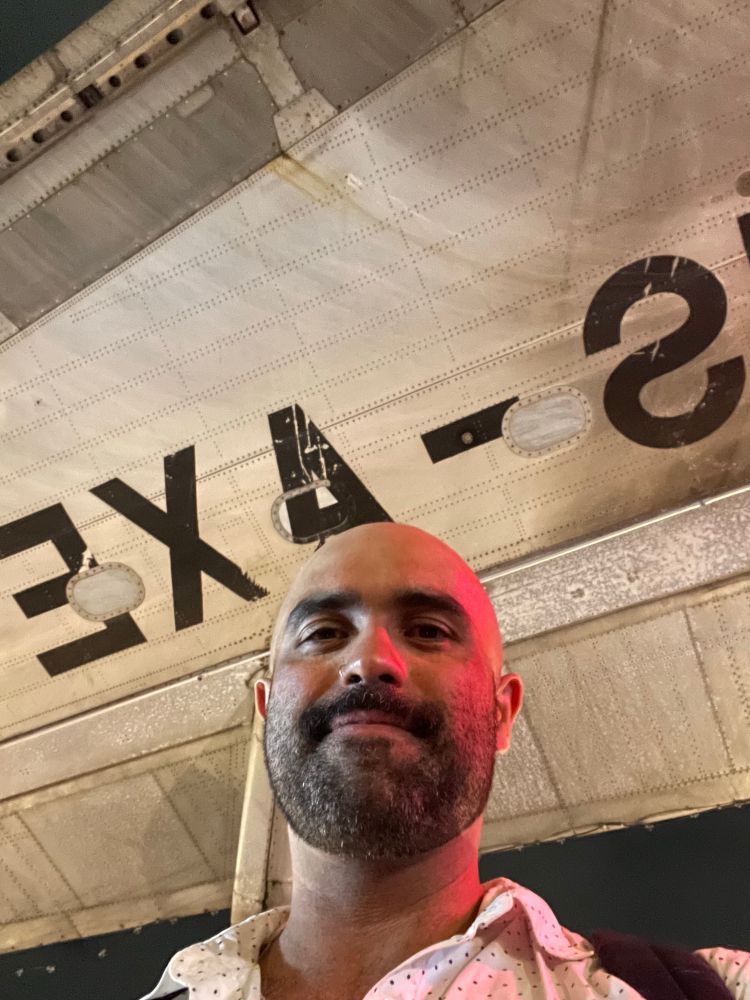 A night market in Thailand that happen, in part  under a decommissioned aeroplane. Yours truly, at best maybe a 5, under the wing. 