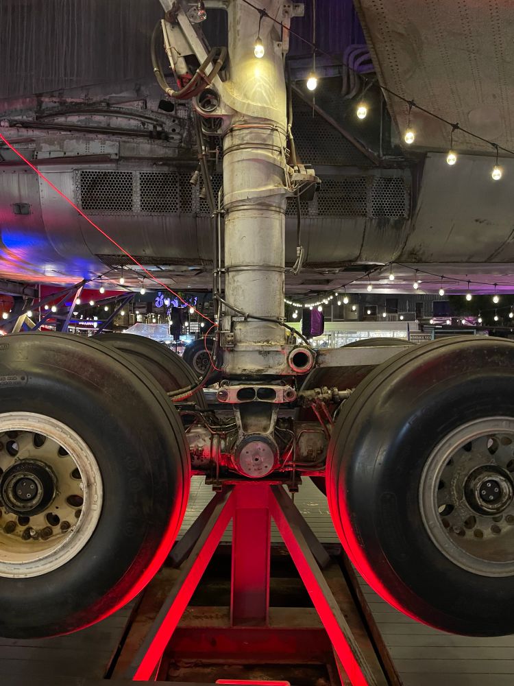 A night market in Thailand that happen, in part  under a decommissioned aeroplane. Close up of the wheels. 