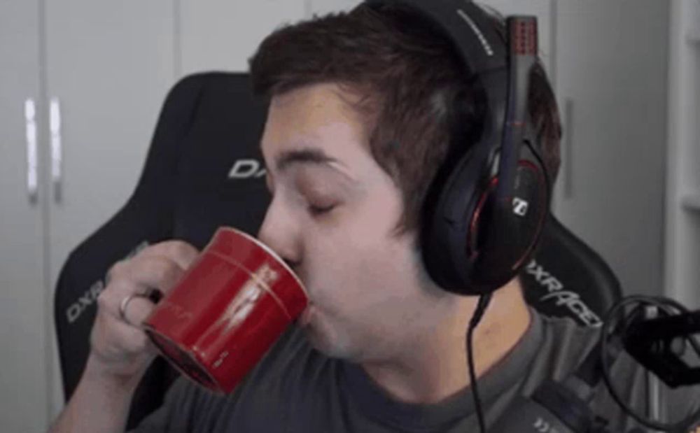 a man wearing headphones is drinking from a red coffee mug